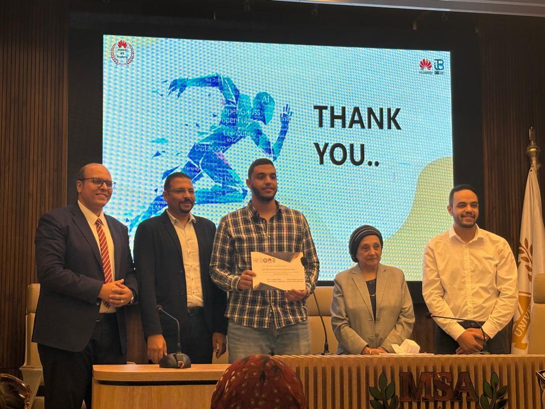 Seif holding his certificate on stage at MSA University during the honoring ceremony, with faculty and organizers